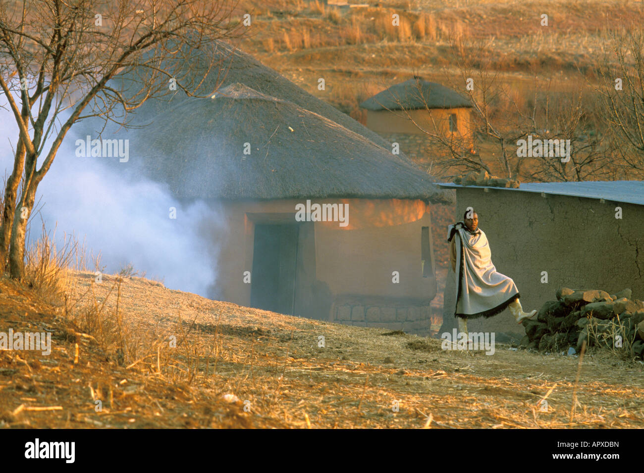 Lesotho Mann vor einem Schlamm und Stroh Gehöft trägt einen traditionellen Umhang Stockfoto