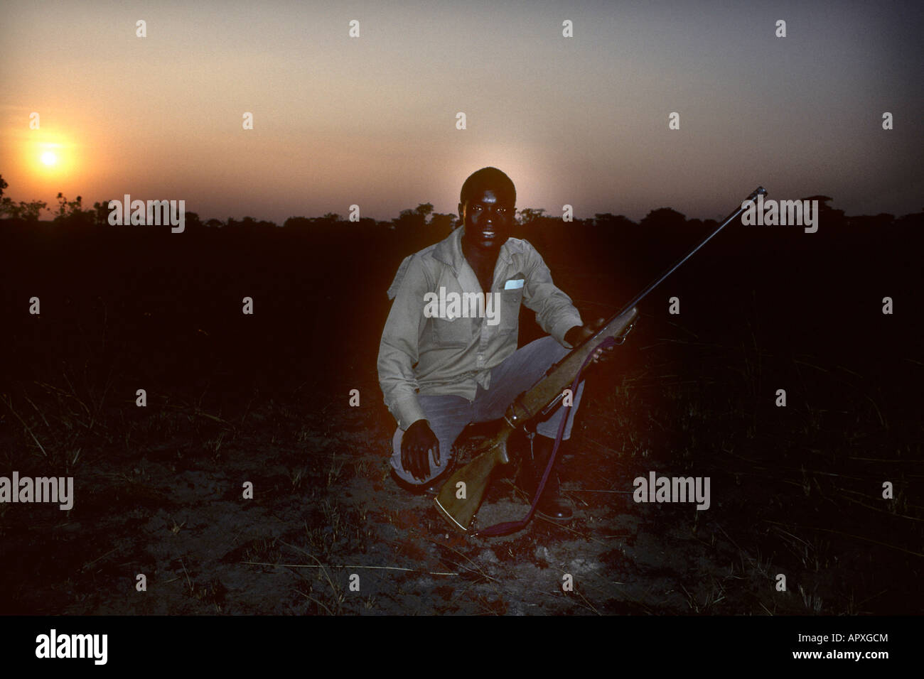 Ranger im Nyika National Park hocken mit einem Gewehr bei Sonnenuntergang Stockfoto