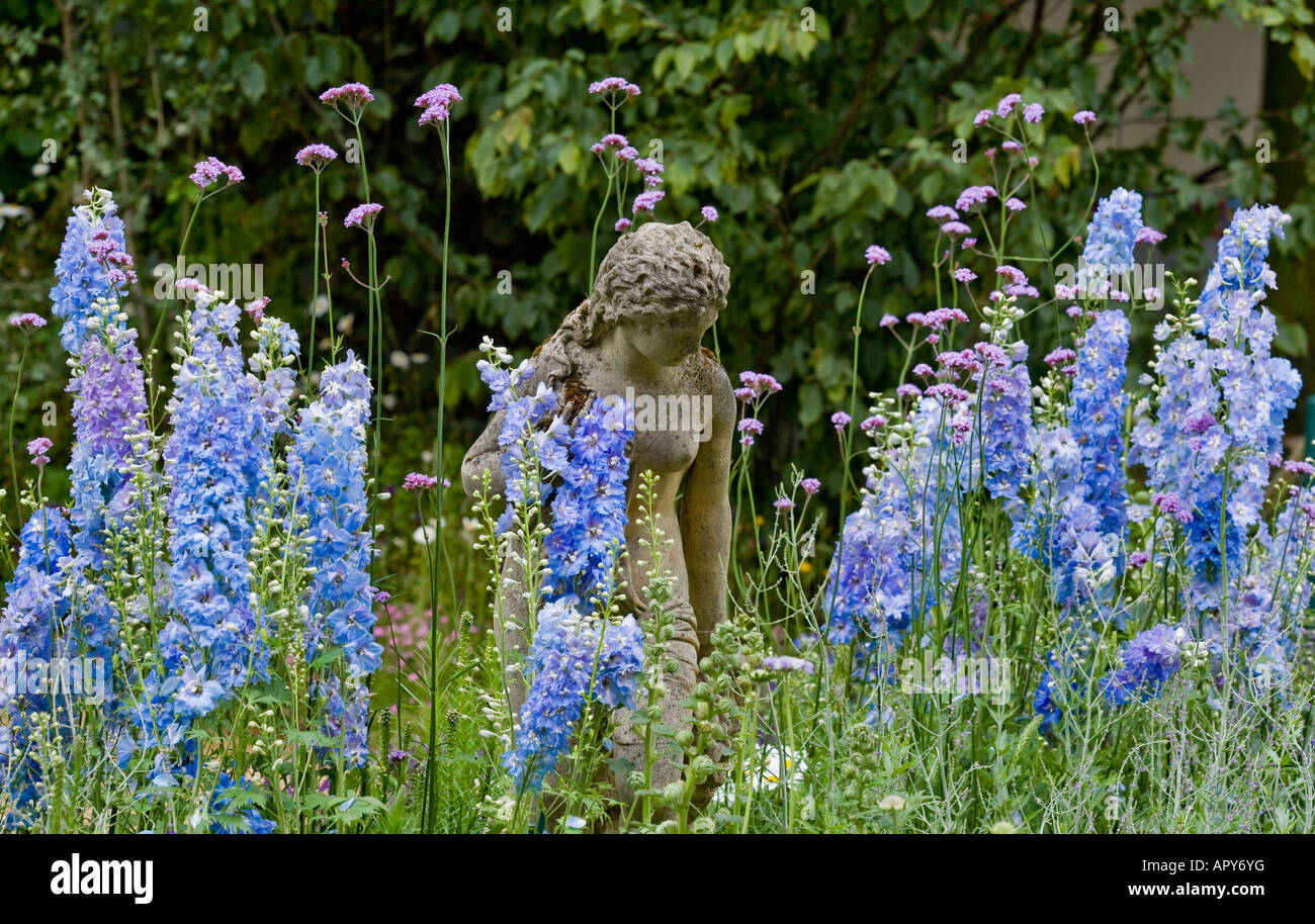 Klassische Statue mit Rittersporn. Rittersporn 'Blauer Dawn', Verbena bonariensis Stockfoto