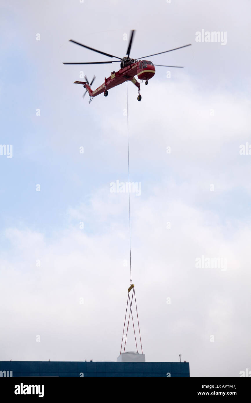 Ein Himmel Kran Hubschrauber liefert eine Klimaanlage an der Spitze eines Geschäftshauses. Stockfoto