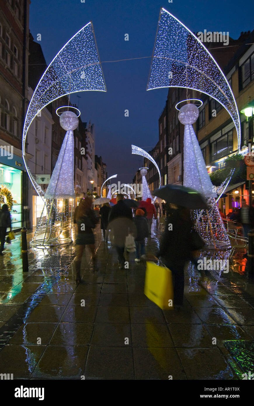 Vertikale Weitwinkel von abstrakten Weihnachtsbeleuchtung Engel und viele Käufer im Zentrum von London in der Regen in der Nacht Stockfoto