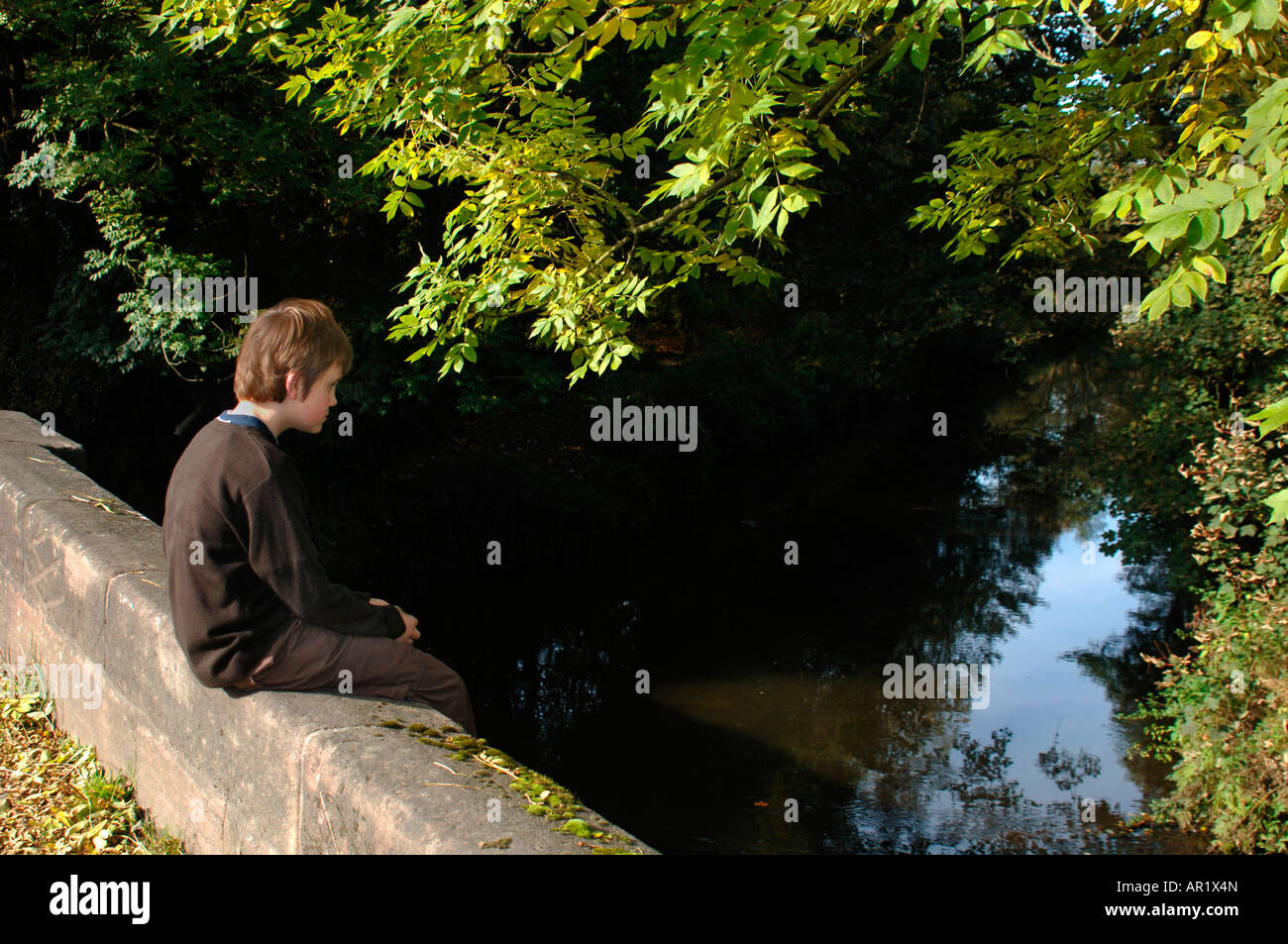 Ein Junge sitzt auf einer Brücke. Stockfoto