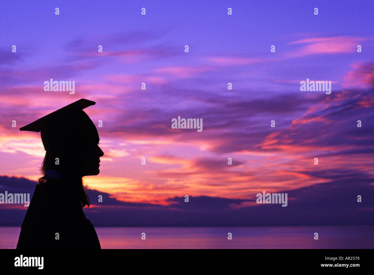 Frau Dipl.-Mütze und Mantel Silhouette gegen bunte Himmel und Meer im Hintergrund 1902 015 11 Stuart Dee Stockfoto