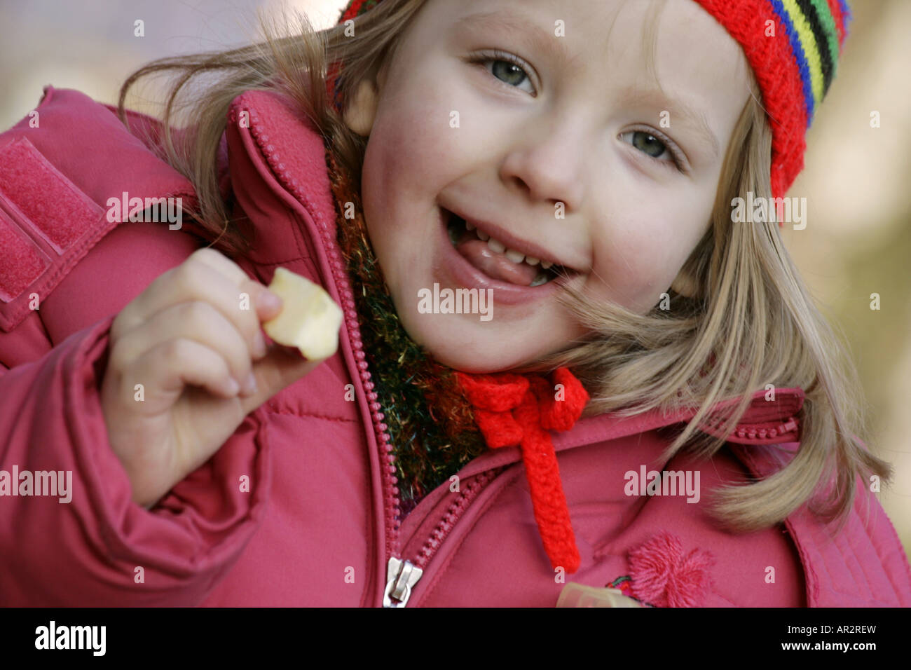 Blondes Mädchen mit einem Stück von einem Apfel in der hand Stockfoto