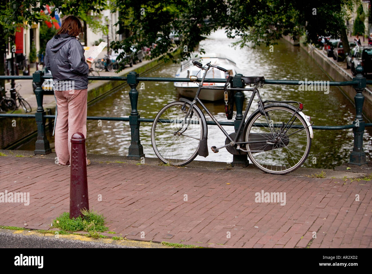 HOLLAND AMSTERDAM TOURENBOOT REISEN AUF EINEM KANAL DURCH EIN FAHRRAD ANGEKETTET AN EINER BRÜCKE MIT BLICK AUF EINE KARTE GESEHEN Stockfoto