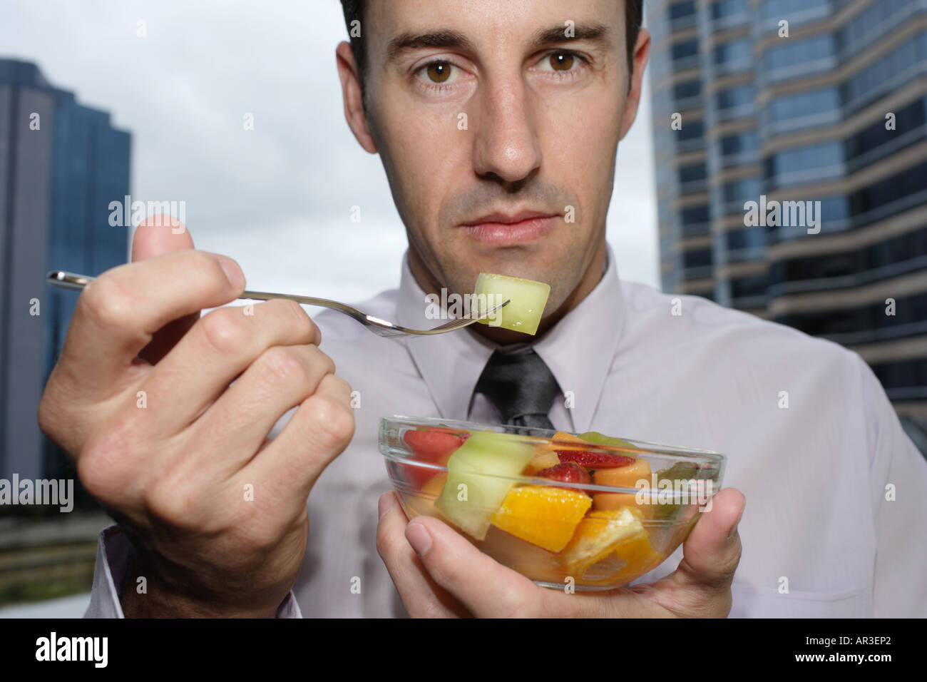 Junger Geschäftsmann hält eine Schale mit frischem Obstsalat Stockfoto