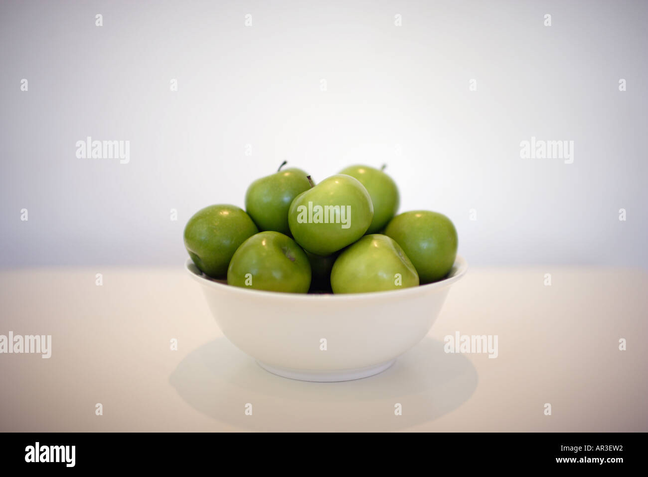 Schüssel voll von grünen Äpfeln auf einem weißen Tisch Stockfoto