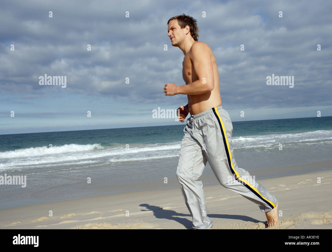 Junger Mann Strand entlang joggen Stockfoto