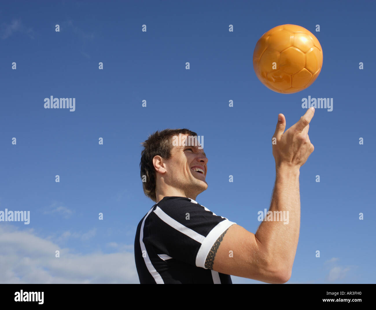 Junger Mann tragen Fußball Shirt Spinnerei Fußball in Luft Stockfoto
