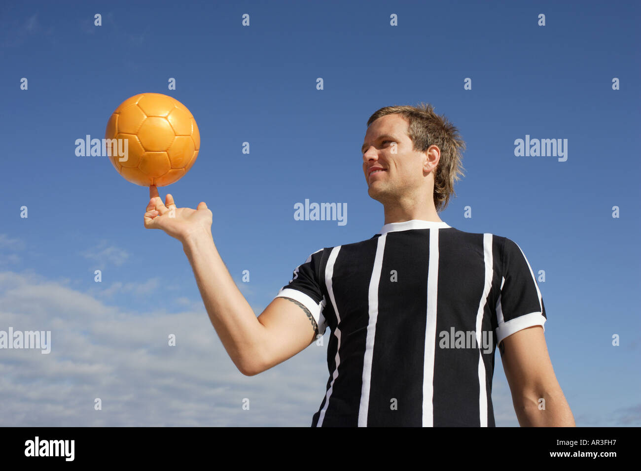 Junger Mann tragen Fußball Shirt Spinnerei Fußball in Luft Stockfoto
