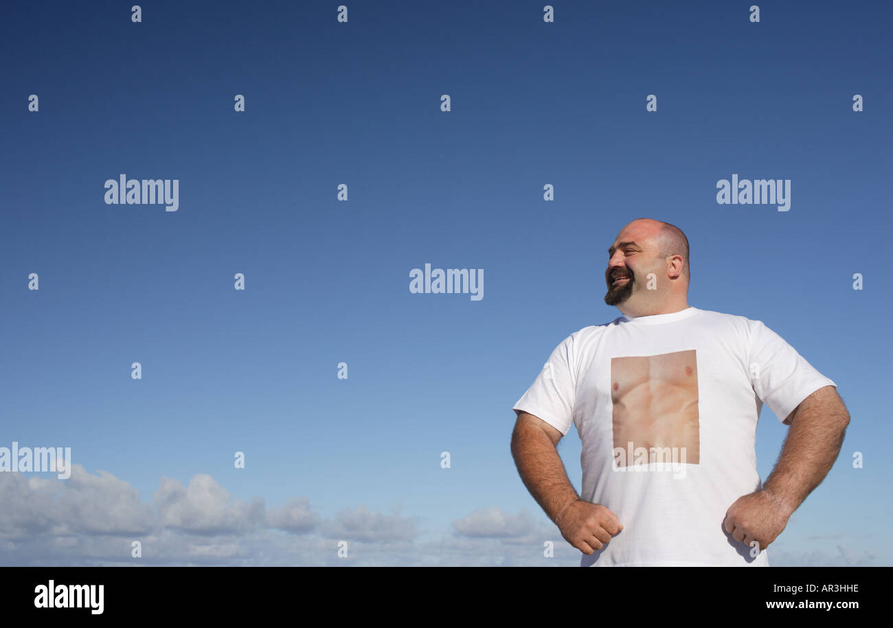 Mann mit T-shirt zeigt eine perfekt getönten Brust stehend gegen blauen Himmel Stockfoto