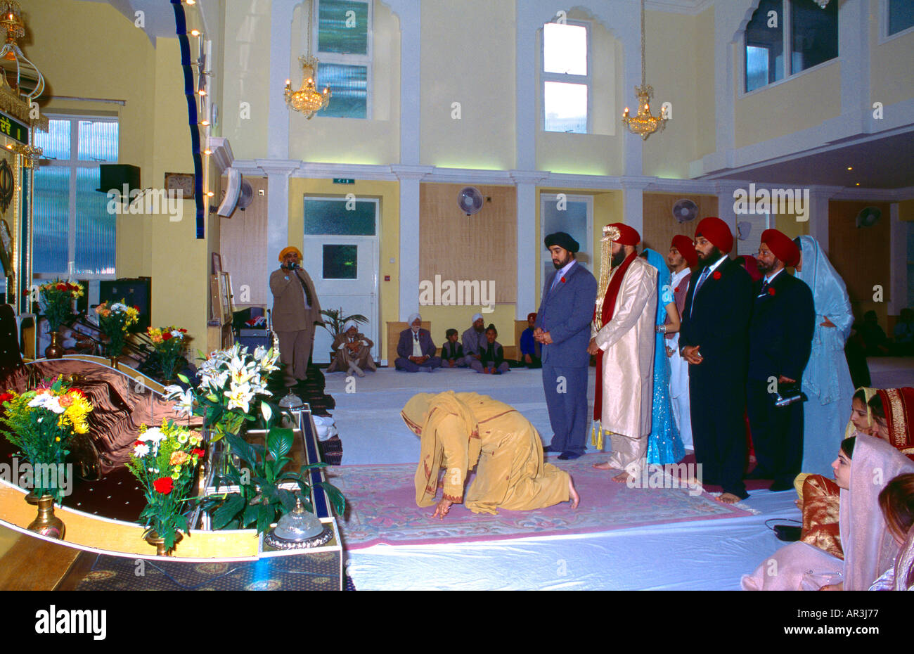 Sikh Hochzeitsgäste Verbeugung vor Granth Central Gurdwara Shepherds Bush London England Stockfoto