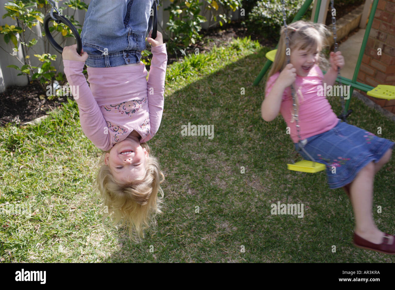 Zwei junge Mädchen auf der Schaukel im Garten spielen Stockfoto