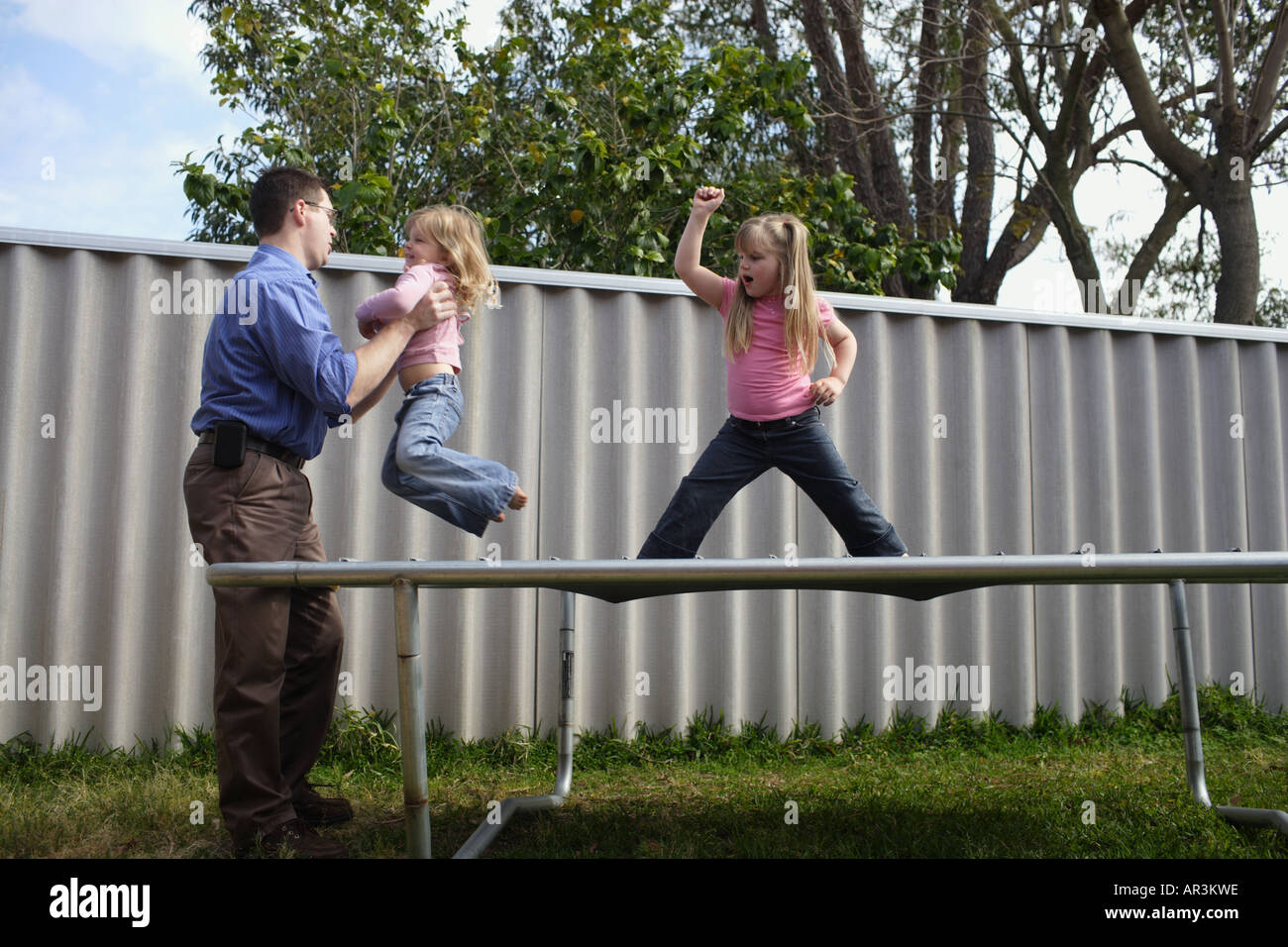 Junge Mädchen stehen auf Trampolin mit Vater Stockfoto
