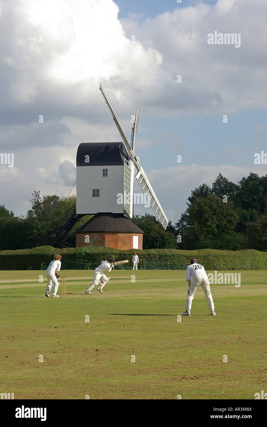 Iconic fundamentale England idyllisches Dorf grün Cricket Match bowler Batsman & Feldspieler Mountnessing Post Mühle darüber hinaus in der Landschaft von Essex UK Stockfoto