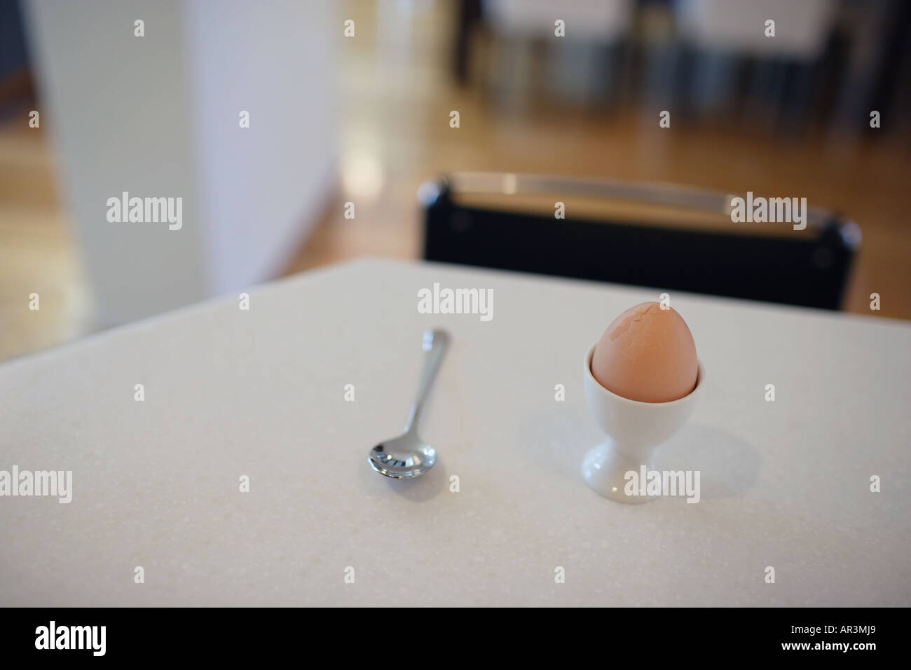 Ein hart gekochtes Ei im Eierbecher mit Löffel auf Tisch Stockfoto