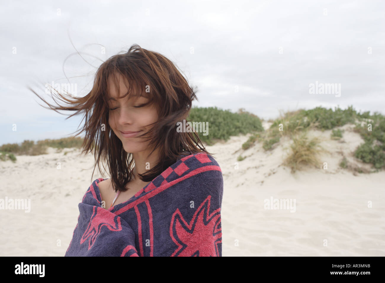 Junge Frau am Strand in Strandtuch, Wind weht Haar gewickelt Stockfoto