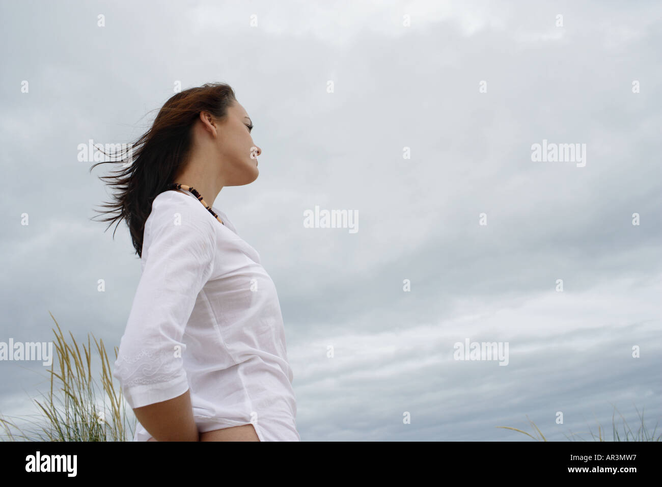 Junge Frau trägt weißes Hemd, bewölkten Himmel aufzublicken Stockfoto