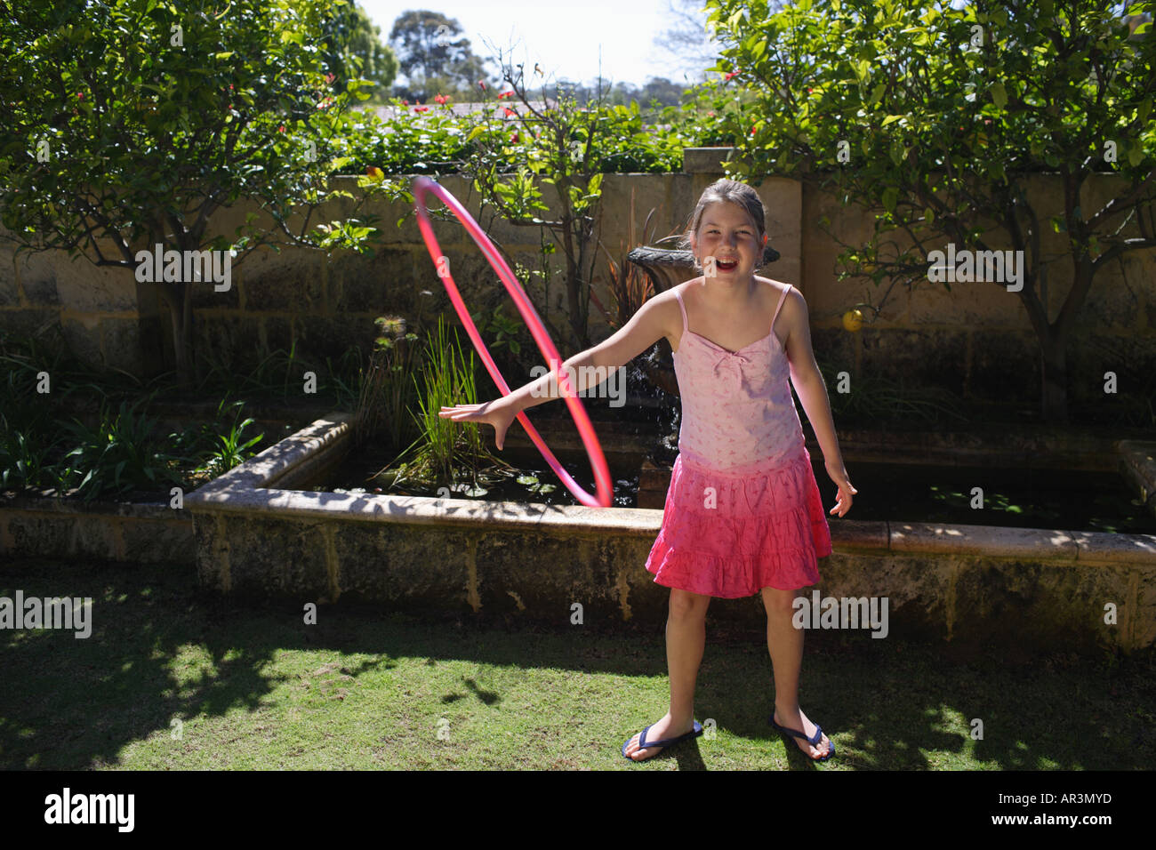 Junges Mädchen mit rosa Hoola Hoop im Garten, lachen Stockfoto