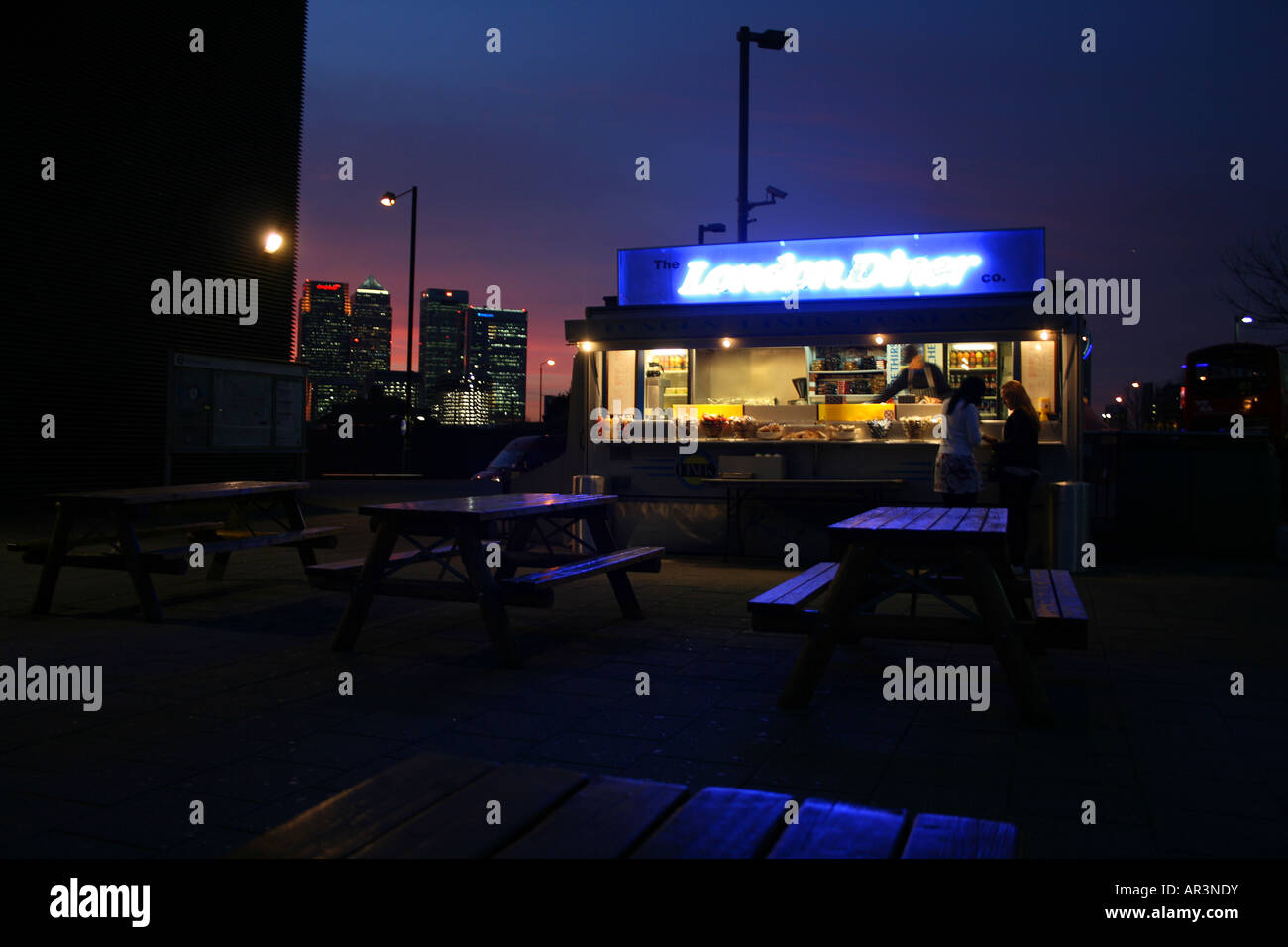 London-Diner dienen außerhalb der Hütte an der North Greenwich Station, London mit Canary Wharf im Hintergrund Stockfoto