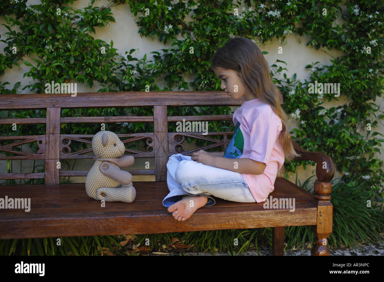 Junges Mädchen sitzen auf Bank Spielzeug Bär Betrachtung Stockfoto