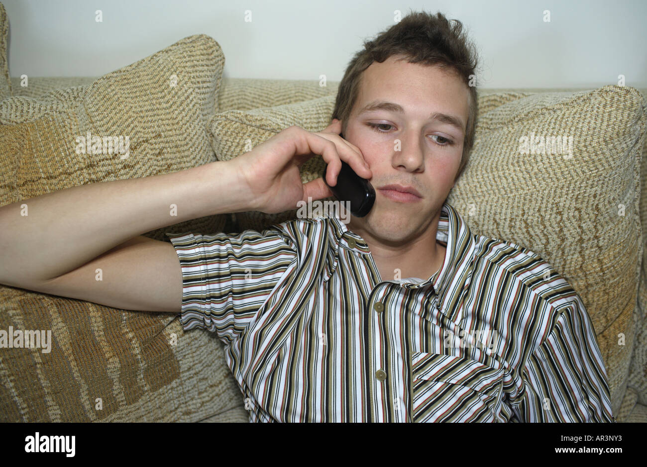 Junger Mann mit Handy auf sofa Stockfoto