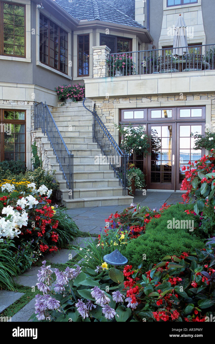 TREPPEN VERBINDEN DIE EBENEN DER GEHOBENEN MINNESOTA HAUSE MIT STAUDENGARTEN IM VORDERGRUND.  FRANZÖSISCH TÜREN.  AMERIKA. Stockfoto