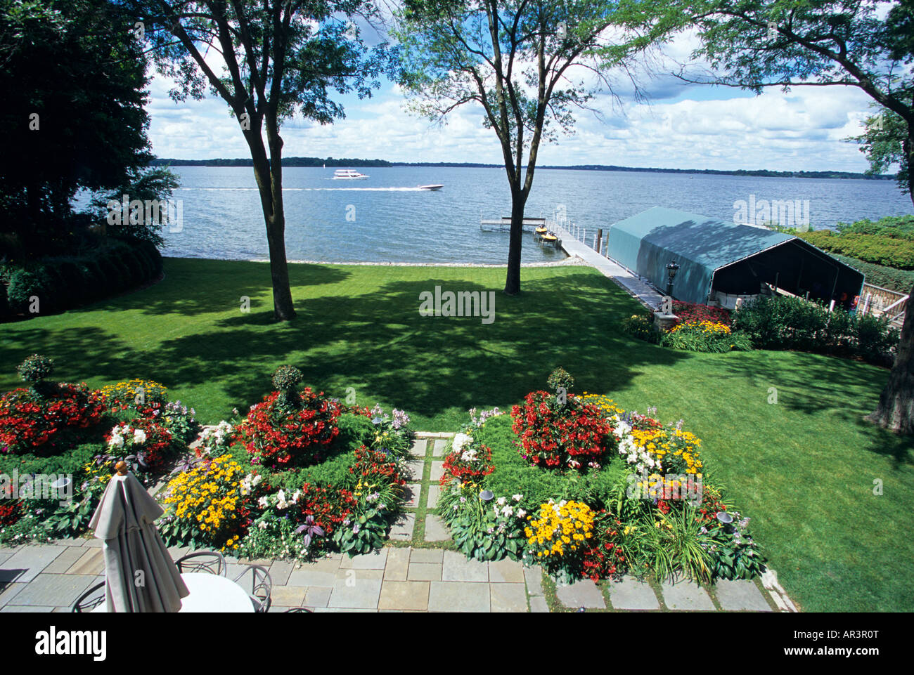 BLICK AUF RÜCKSEITE TERRASSE GARTEN VON MINNESOTA SEE ZUHAUSE AN EINEM SOMMERTAG MIT BOOTSHAUS UND DOCK.  AMERIKA. Stockfoto
