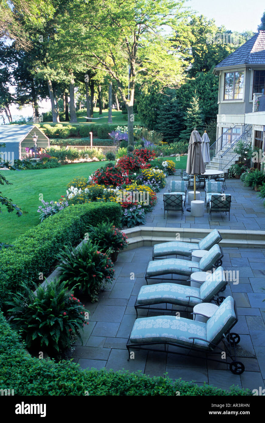 TERRASSE VON MINNESOTA LAKE HOME GRENZT MIT EINER GEMISCHTEN GARTEN STAUDEN UND EINJÄHRIGEN PFLANZEN, EINSCHLIEßLICH DER ALGERISCHEN IVY ZURÜCK. SOMMER. Stockfoto