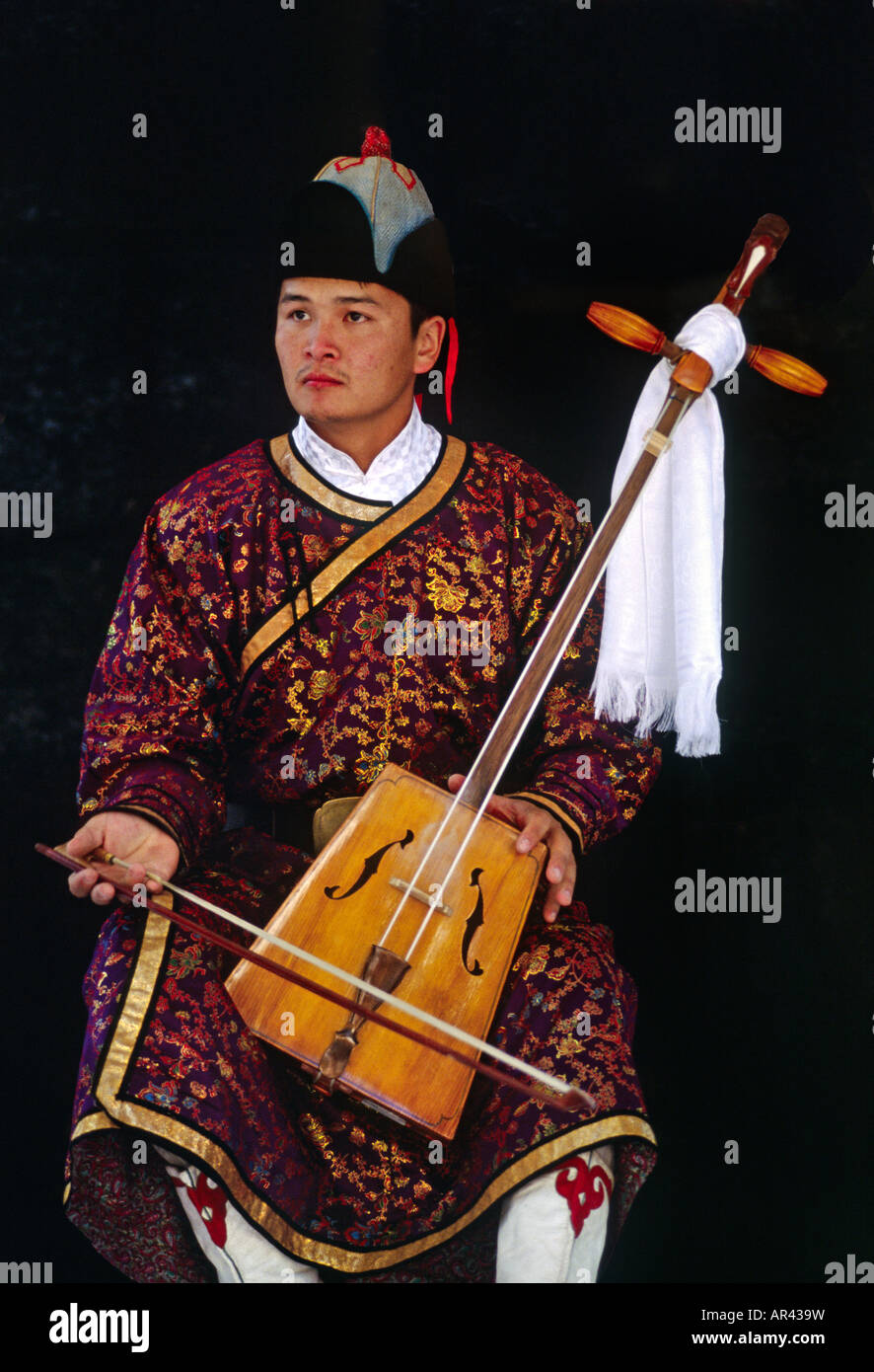 MONGOLISCHER Musiker in historischer Kleidung spielt ein traditionelles SAITENINSTRUMENT aus der Mongolei Stockfoto