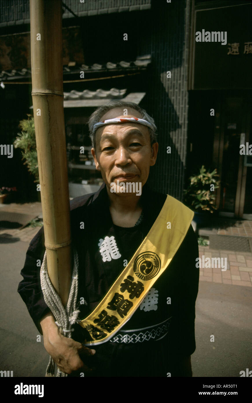 Ein Mann trägt einen Stock, um Telefonleitungen vom oberen Rand einen Mikoshi (tragbarer Schrein) während einer Matsuri in Tokyo zu bewegen Stockfoto