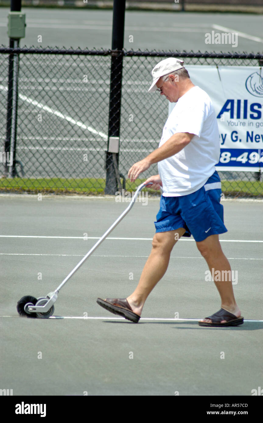 Mann, die Reinigung von Leitungen auf Sand-Tennisplatz Stockfoto