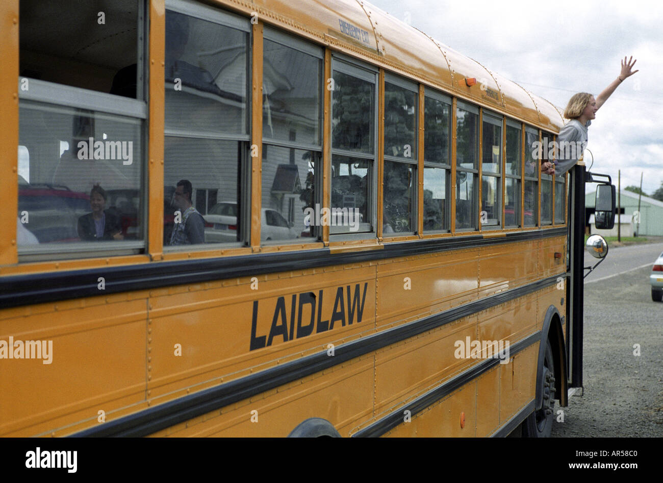 Student-Wellen aus Fenster des Busses am letzten Schultag Stockfoto