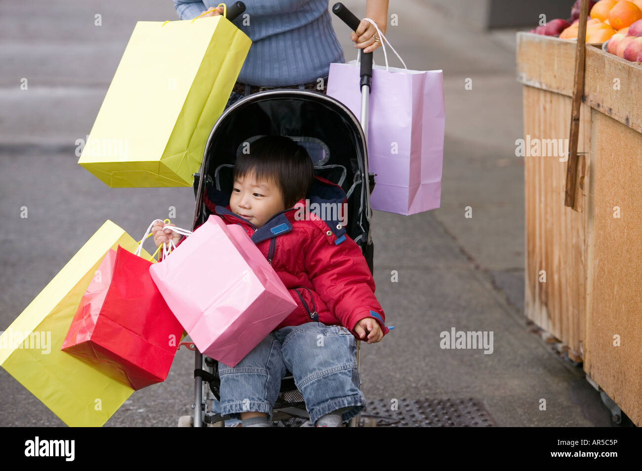 Junge im Kinderwagen mit Einkaufstüten Stockfoto