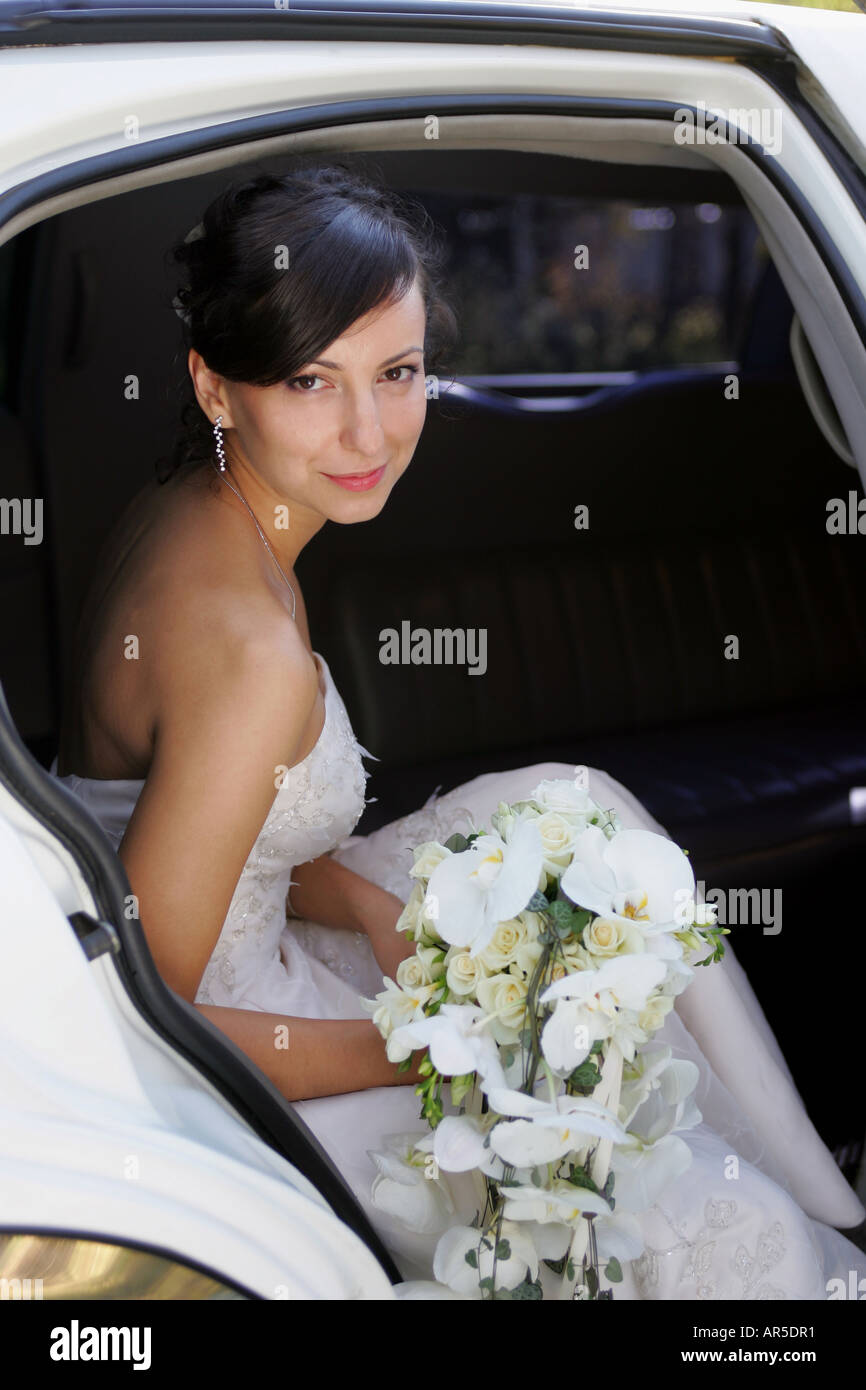 Ein Porträt einer schönen Braut an ihrem Hochzeitstag saß in ihrem Hochzeitsauto hält einen Blumenstrauß Stockfoto
