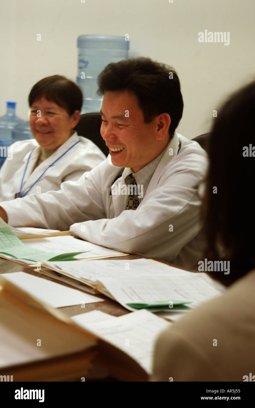 Doctor laughs during staff meeting: Vietnamese-American community clinic, Garden Grove, California, USA. MODEL RELEASE Stockfoto