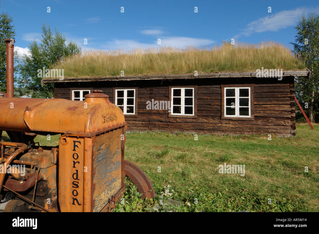 Alte Fordson Traktor und historische Gebäude aus Holz, das Open Air Museum in der Nähe von Bardufoss, Norwegen Stockfoto