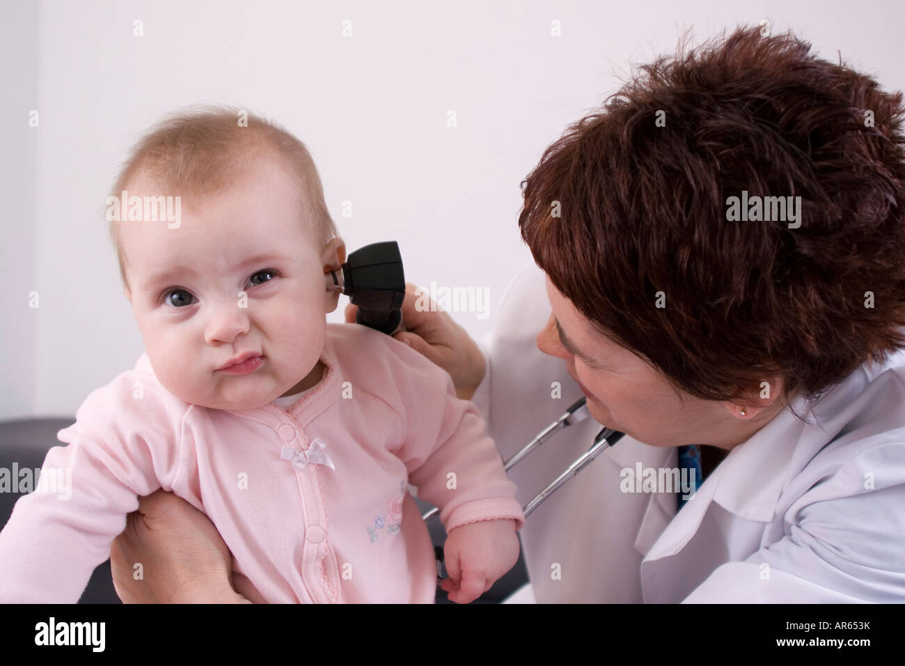 Kinderarzt mit einem Otoskop in ein Baby s Ohr schauen Stockfoto