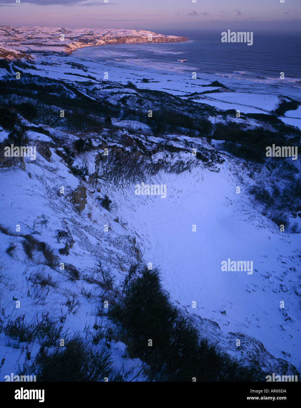 Robin Hoods Bay aus der Ravenscar Alaun Steinbrüchen in der Wintersonne mit Landzunge und Felder, die mit Schnee bedeckt Stockfoto