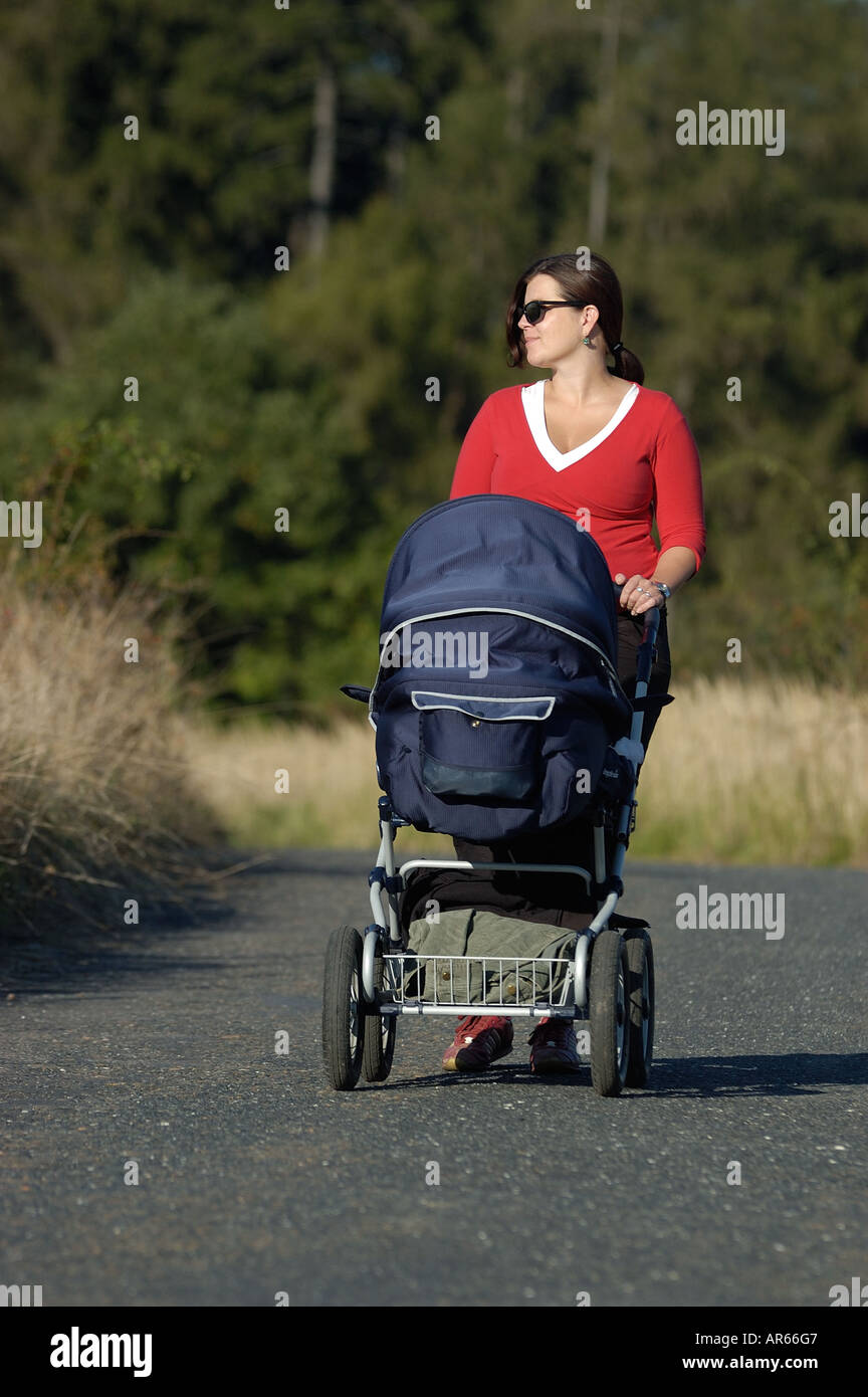 Porträt einer jungen Frau, die einen Baby Kinderwagen schieben, auf der Reise Stockfoto