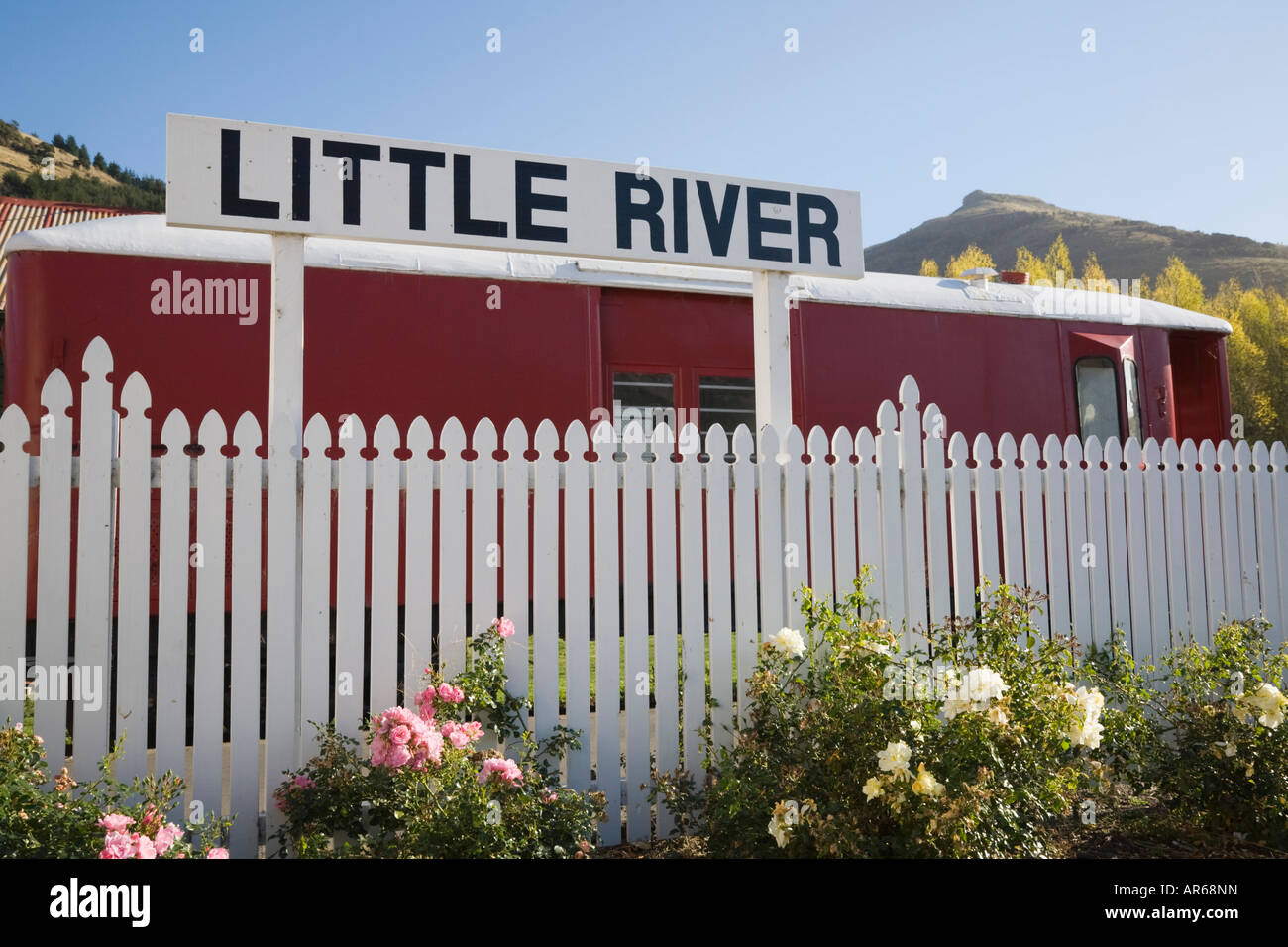 Dorf legen Namensschild auf weißen hölzernen Lattenzaun vor alten Bahnhof "Little River" New Zealand Stockfoto
