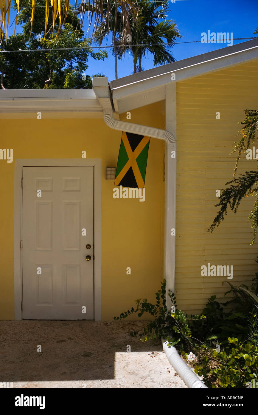 Der jamaikanische Flagge hängt vor einem leuchtend gelben Haus in den Tropen Stockfoto