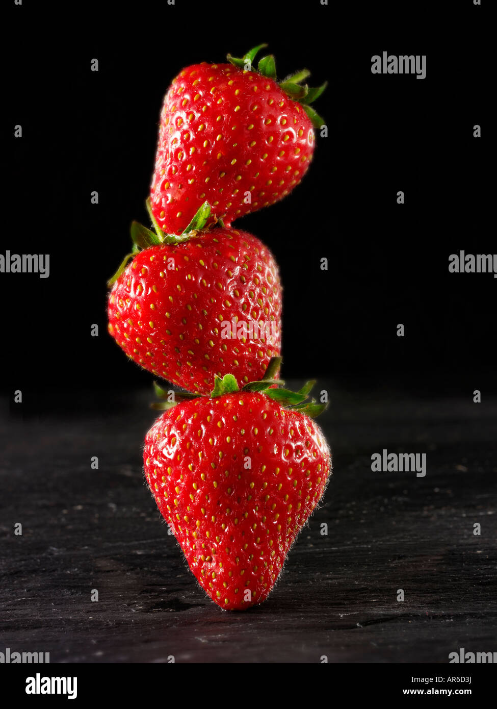 Stapel von frischen Englisch Bio Erdbeeren vor einem schwarzen Hintergrund, stilisierte kreatives Konzept Foto Stockfoto