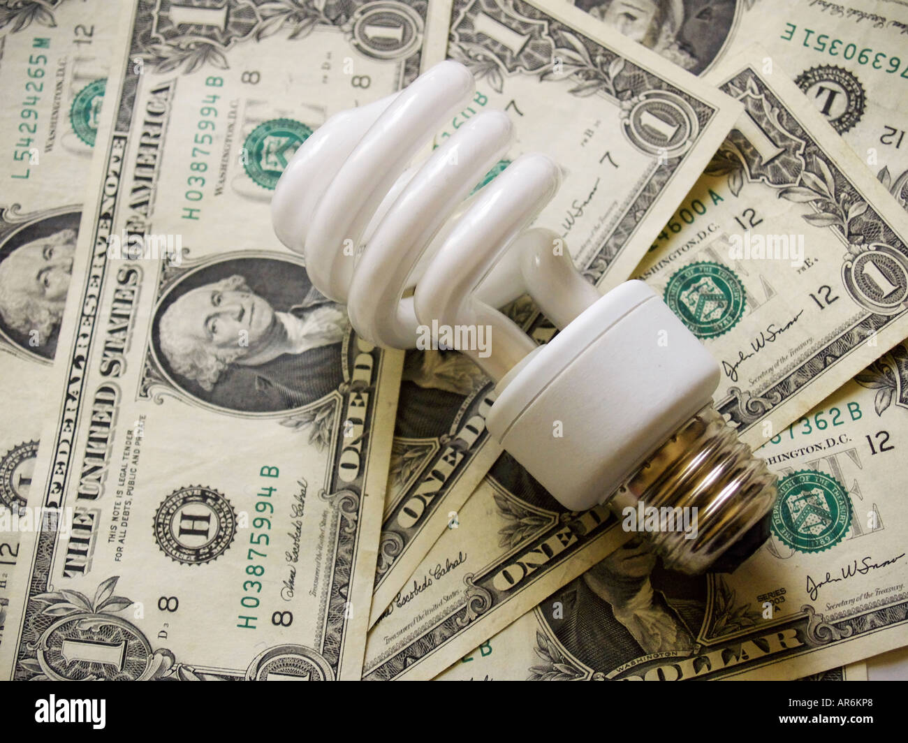 Spiralförmigen Leuchtstoff Glühlampe vor dem Hintergrund einer Dollar-Scheine. Stockfoto