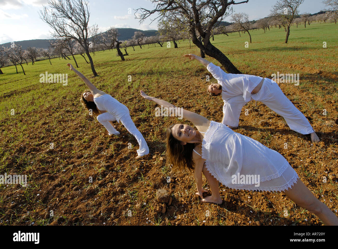 Herr drei Menschen, ein Schwedisch-Mann, eine Brasilianerin und eine Spanierin, üben von Yoga in den Bereichen von Ibiza, Spanien Stockfoto