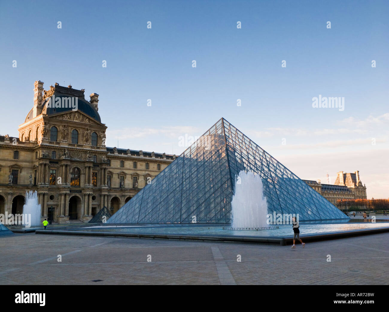 Jogger laufen rund um die Louvre-Pyramide am Louvre-Museum, Paris, Frankreich, Europa in den frühen Morgenstunden Stockfoto