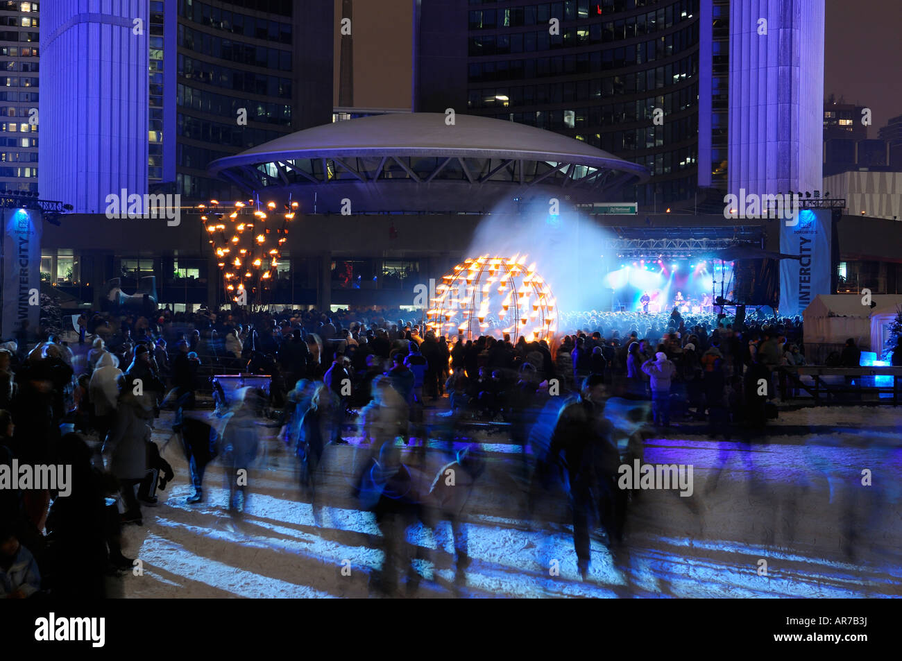 Verschwommene Skater in der Toronto City Hall während Wintercity Nights of Fire mit dem aufgenommen zeigen Nathan Philips Square im winter Stockfoto Verschwommene Skater in der Toronto City Hall während Wintercity Nights of Fire mit dem aufgenommen zeigen Nathan Philips Square im winter Stockfoto