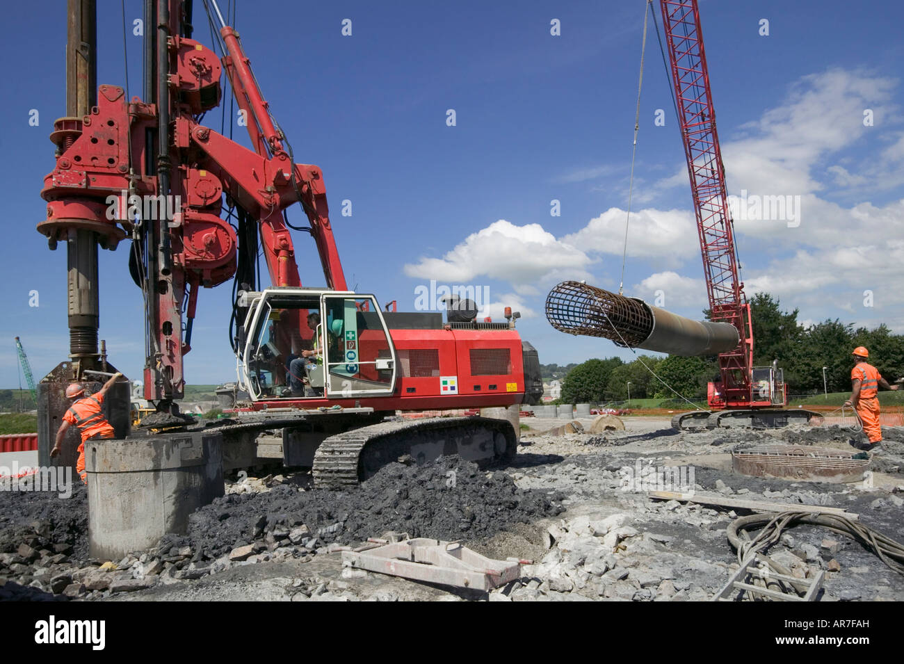 Riesige Anhäufung Rig Entladung verwöhnen.  Hinter hebt ein Kran eine verstärkte Stahlkäfig, in Haufen einzufügen, bevor Beton hinzugefügt wird. Stockfoto
