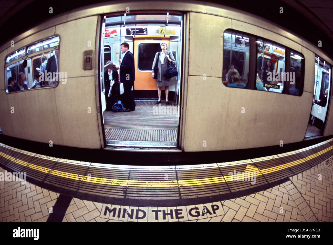 District Line u-Bahn auf einem Bahnsteig in London. Fotografiert mit einem Fischaugen-Objektiv, damit die Verzerrung. Stockfoto