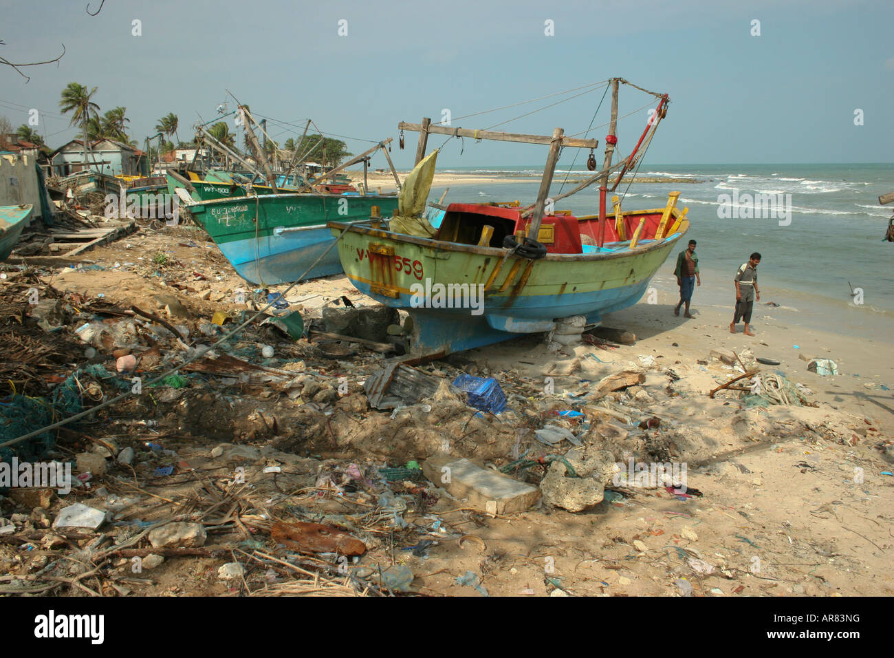 Zwei Männer, die zu Fuß auf den Strand von Jaffna Halbinsel bedeckt mit Müll und Boote beschädigt, nach der Tsunami im Dezember 04 struck Stockfoto